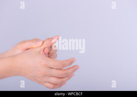 Femme souffrant de douleur à la main sur fond gris. Banque D'Images