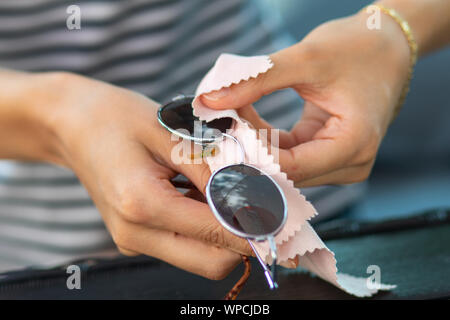 Mains femme nettoyer ses lunettes de soleil avec lingette en microfibre, lunettes d'essuyage Banque D'Images