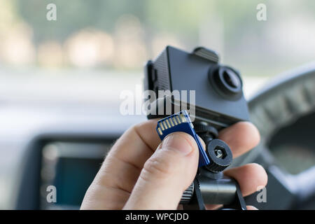 La main d'un conducteur de voiture de mâles qui détient une voiture DVR enregistrement des incidents et une carte mémoire pour elle Banque D'Images