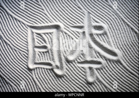 Jardin zen japonais avec les caractères chinois pour Nihon (traduction anglaise : le Japon) écrit dans le sable blanc texturé avec ratissées résumé modèle d'onde Banque D'Images