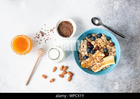 Petit-déjeuner ou à l'avoine avoine porridge aux fruits, graines de lin, le miel dans un bol. Vue de dessus de table. Petit-déjeuner sain ingrédients alimentaires, manger propre concept Banque D'Images