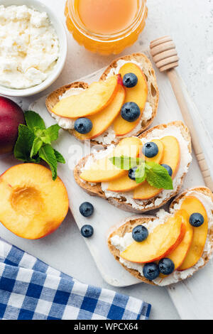 Fruit sucré bruschetta à la ricotta, miel et pêche blanche en bois servant de bac. Vue de dessus Banque D'Images