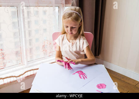 Portrait of a cute little girl painting mains à la maison. Apprendre, l'éducation, l'enfance heureuse concept Banque D'Images