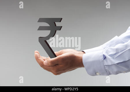 Main de la personne montrant le symbole de roupie indienne Banque D'Images