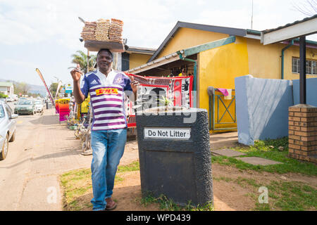 La rue africaine vendeur vend une sélection de noix et les transporte sur sa tête dans une rue à Graskop, Mpumalanga, Afrique du Sud travaille en tant que commerçant informel Banque D'Images