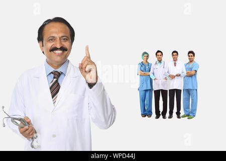 Médecin de sexe masculin pointant vers le haut avec l'équipe en arrière-plan Banque D'Images