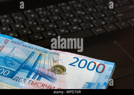 Un paquet de roubles russes d'une valeur nominale de 2000 roubles se trouve sur le clavier d'ordinateur portable. Vue d'en haut. Banque D'Images