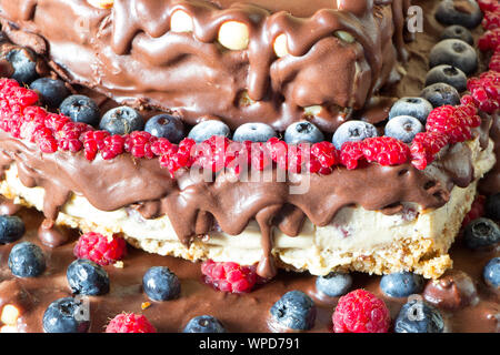 Close up matières cheesecake vegan sain avec du chocolat, framboises, bleuets et les écrous. Régime alimentaire des matières premières. Banque D'Images
