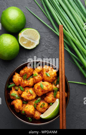 Dans un bol de Manchourie Gobi à fond béton noir. Mandchourie Gobi est Indian cuisine Chinoise avec le chou-fleur, tomates, oignons, sauce de soja. Banque D'Images