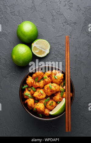 Dans un bol de Manchourie Gobi à fond béton noir. Mandchourie Gobi est Indian cuisine Chinoise avec le chou-fleur, tomates, oignons, sauce de soja. Banque D'Images