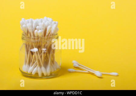 Coton-tiges de bambou réutilisables dans un bocal en verre sur le fond jaune. Concept zéro déchet, plastique, produits bio, eco-friendly shopping Banque D'Images