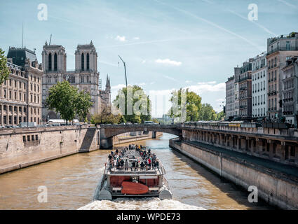 Un bateau de plaisance avec les touristes à bord effectue une excursion guidée de la Seine dans le Paris historique avec vue sur la cathédrale Notre Dame une Banque D'Images