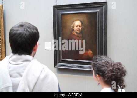 Un jeune couple debout devant le autoportrait à l'âge de 63 ans par le peintre hollandais Rembrandt à la National Gallery, Londres, Royaume-Uni Banque D'Images