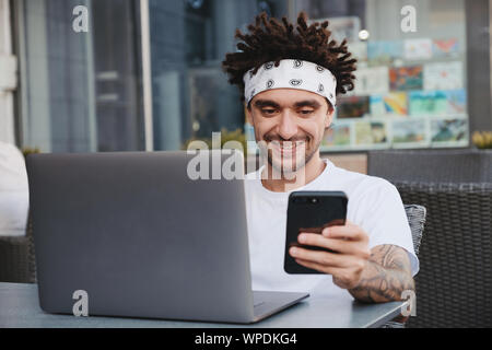 Hipster heureux guy holding smartphone, excité avec de bonnes nouvelles s'en message sms, recevoir le paiement, gagnant du concours en ligne sur le site web. Cheerful youn Banque D'Images