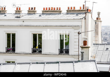 Pots de fleurs suspendus dans les fenêtres de l'étage mansardé et sur le balcon de l'immeuble de plusieurs étages - Un design architectural classique du vieux Pari Banque D'Images