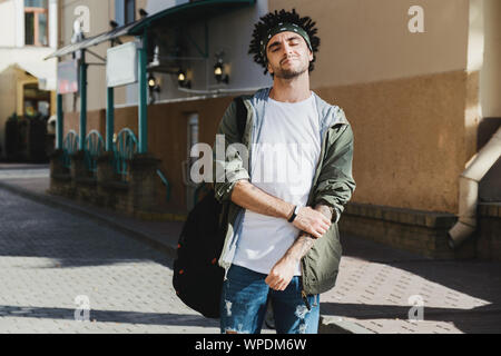 Beau jeune homme barbu avec des dreadlocks hairstyle habillé des vêtements à la mode de profiter de la vie. La mode d'automne tenue, outdoor portrait, style urbain, Banque D'Images