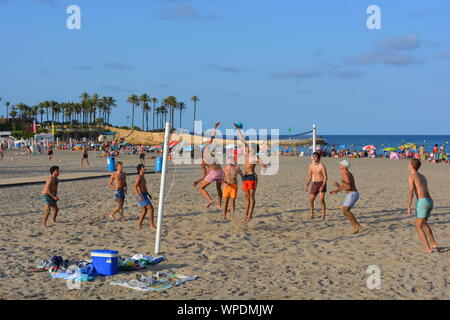 Groupe de jeunes hommes jouant au beach-volley sur la plage Arenal de Javea sur la Costa Blanca, Espagne. La fin de l'après-midi dans l'été Banque D'Images