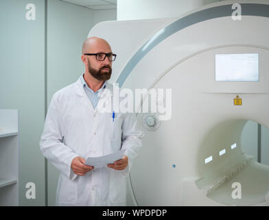 Médecin avec une carte médicale du patient près de scanner IRM dans un hôpital Banque D'Images