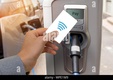 Un homme paie pour la recharge d'une voiture électrique. Banque D'Images