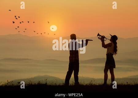 Musicien jouer la flûte et la trompette avec coucher et au lever du soleil contexte Banque D'Images