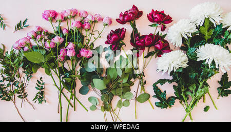 Différentes fleurs d'une télévision à jeter. Les pivoines, roses rose mauve, des chrysanthèmes blancs et des branches vertes sur fond rose pastel, vue du dessus. Tex Fleurs Banque D'Images