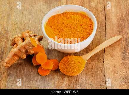 Le curcuma racines avec poudre de curcuma sur fond de bois Banque D'Images