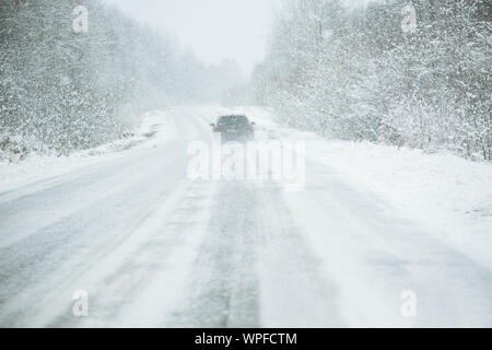 La voiture roule sur une route d'hiver dans un blizzard Banque D'Images