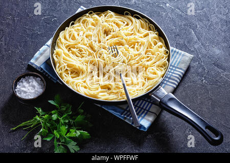 Close-up of belrom e pepe, pâtes mélangées avec du fromage pecorino râpé et saupoudrées de poivre noir fraîchement moulu dans une poêle avec une fourchette, vue de abov Banque D'Images