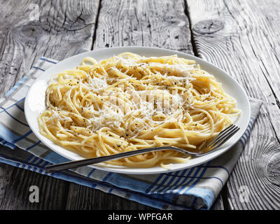 Spaghettis à la crème de fromage et saupoudrées de poivre noir sur une plaque blanche sur une table en bois rustique, belrom e pepe, la cuisine italienne, vue d'un Banque D'Images