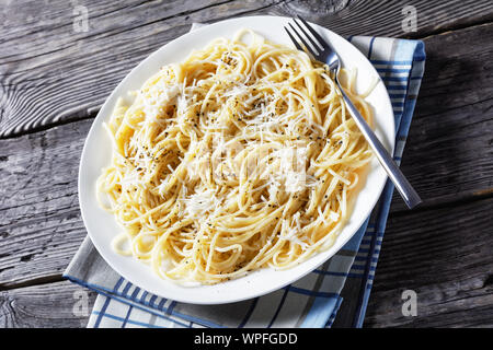 Spaghettis à la crème de fromage et saupoudrées de poivre noir sur une plaque blanche sur une table en bois rustique, belrom e pepe, la cuisine italienne, vue d'un Banque D'Images