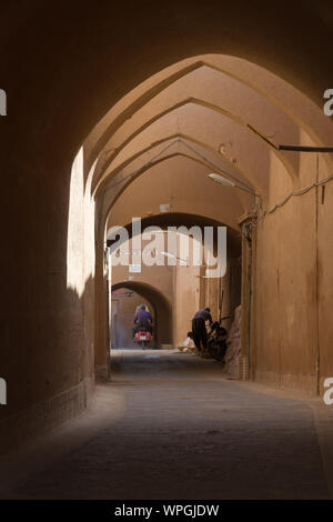 YAZD, IRAN - 2 octobre 2017 : deux habitants dans une ruelle voûtée dans le centre historique de la ville de Yazd, Iran désert. Célèbre pour sa boue adobe (brique) Banque D'Images