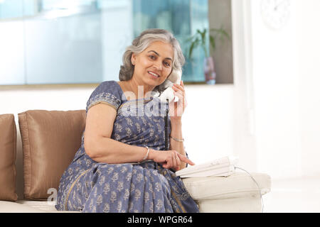 Senior woman dialing sur un téléphone fixe Banque D'Images