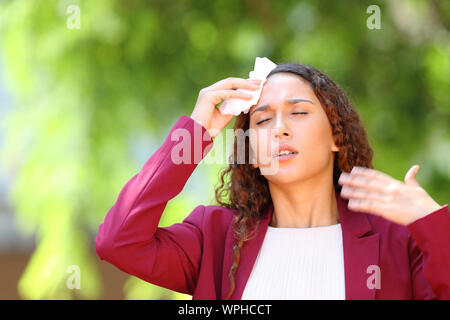 Souligné mixed race woman wearing jacket souffrant d'un coup de chaleur dans un parc Banque D'Images