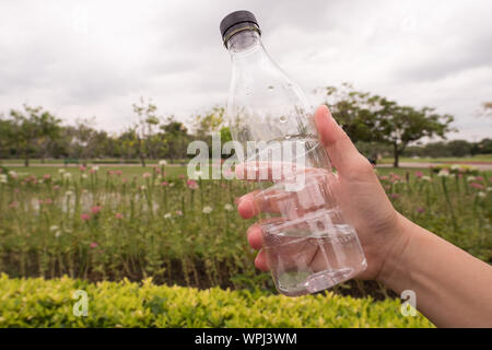 Main tenant une bouteille d'eau en plastique dans le jardin. Banque D'Images
