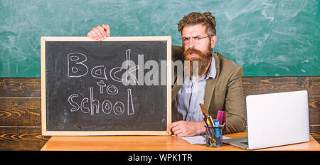 Bienvenue à nouveau. Enseignant accueille de nouveaux élèves à entrer dans l'établissement d'enseignement. Début de nouvelle année scolaire en septembre. Enseignant ou directeur d'école accueille avec tableau noir inscription retour à l'école. Banque D'Images