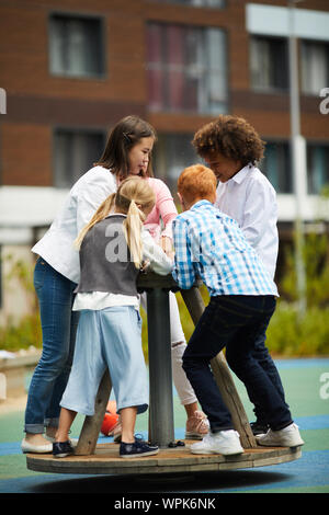 Groupe d'enfants multiethnique heureux de jouer et s'amuser ensemble sur l'aire de jeux en plein air Banque D'Images