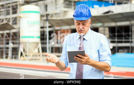 Ingénieur Senior man in suit et le casque de travailler sur tablet pc Banque D'Images