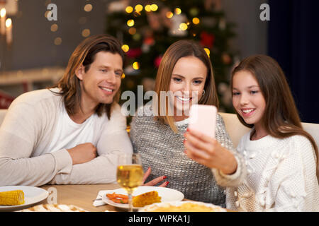 Belle famille célébrer Noël à la maison et prendre des selfies Banque D'Images