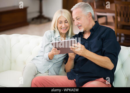 D'âge mûr à l'aide d'une tablette numérique dans leur appartement Banque D'Images