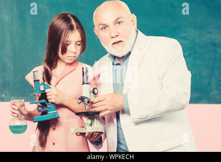 L'industrie chimique. mature professeur de biologie. Élève à l'école de fille lab. Petite fille avec l'homme tuteur étudier la chimie. utiliser loupe. classe de sciences. Microscopie électronique. Matériel de laboratoire. Banque D'Images