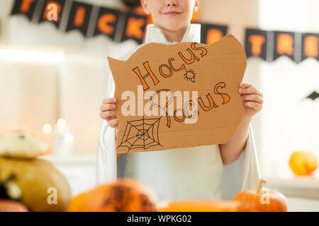 Close-up of boy holding Hocus Pocus placard tout en visitant Halloween party Banque D'Images