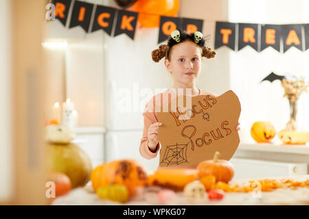 Portrait de fille mignonne avec Hocus Pocus placard looking at camera tout en visitant Halloween party Banque D'Images