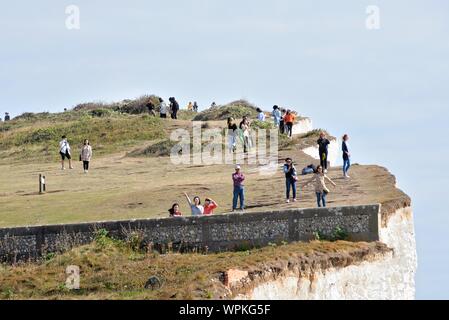 Les jeunes touristes coréens à prendre des photos debout sur le bord de la falaise de craie à Urrugne Eastbourne East Sussex England UK Banque D'Images