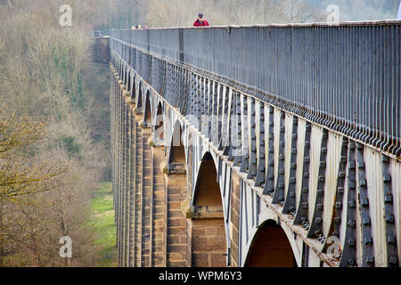 Vue le long du côté de l'Aqueduc de Pontcysyllte portant le canal de Llangollen sur la rivière Dee dans Denbighshire Pays de Galles avec un homme en rouge marche à travers Banque D'Images