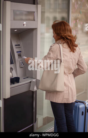 Une femme mature, à l'aide d'un guichet automatique, insertion de carte de crédit dans la machine. Banque D'Images