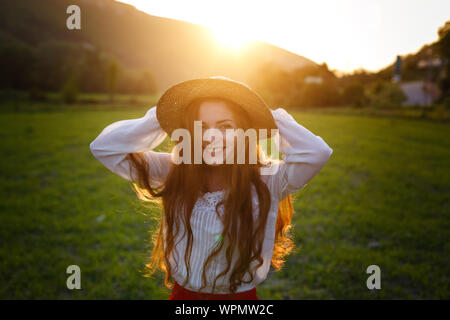 Portrait de l'été, belles jeunes rousseur woman wearing Straw Hat à l'heure du coucher du soleil sur le terrain Banque D'Images