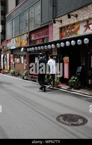 MATSUYAMA, JAPON - 20 juil 2019 : un tir vertical de deux hommes marchant le long d'une route près de boutiques de rue Banque D'Images