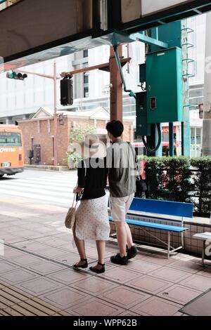 MATSUYAMA, JAPON - 20 juil 2019 : un tir vertical d'un homme et une femme portant des vêtements d'été à marcher le long d'un trottoir Banque D'Images