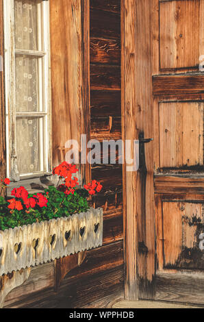 Chalet en bois avec des fleurs rouges dans les fenêtres. Chalet alpin. Cabanes en Bavière. Décorations florales. Fleur traditionnelle, style. La Bavière, Autriche, Suisse. Les alpes. Banque D'Images