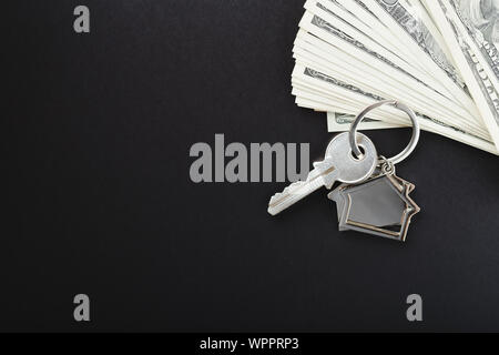 Clés de la maison au cours de la centaine de billets de dollar sur fond noir. Banque D'Images
